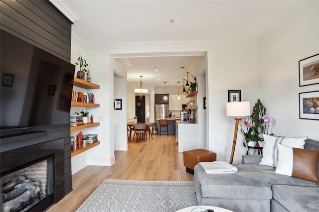 living room featuring baseboards, a fireplace, light wood-style flooring, and crown molding