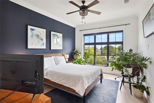 bedroom with visible vents, wood finished floors, a ceiling fan, and crown molding