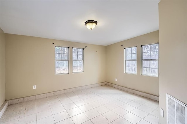 empty room with light tile patterned floors and a healthy amount of sunlight