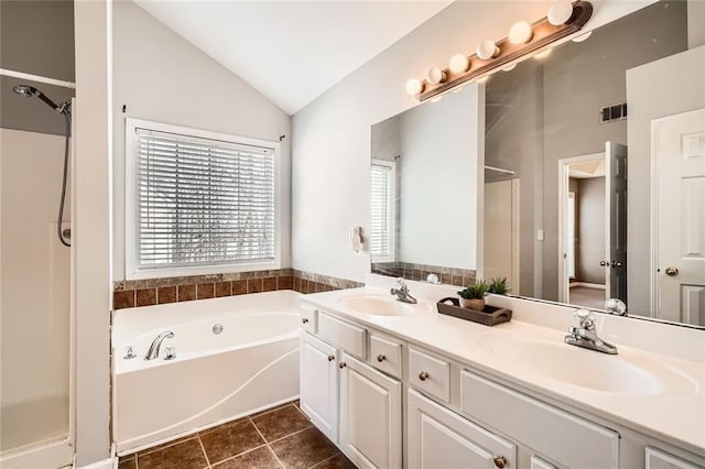 bathroom with tile patterned floors, vanity, vaulted ceiling, and a tub