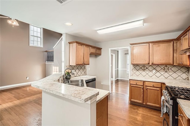 kitchen with backsplash, kitchen peninsula, sink, and stainless steel appliances