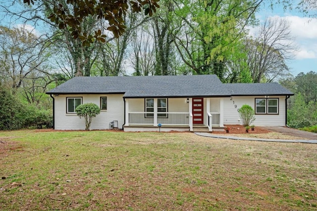 single story home featuring covered porch, roof with shingles, and a front lawn