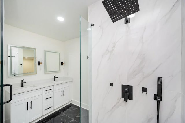 bathroom with a sink, double vanity, and a marble finish shower