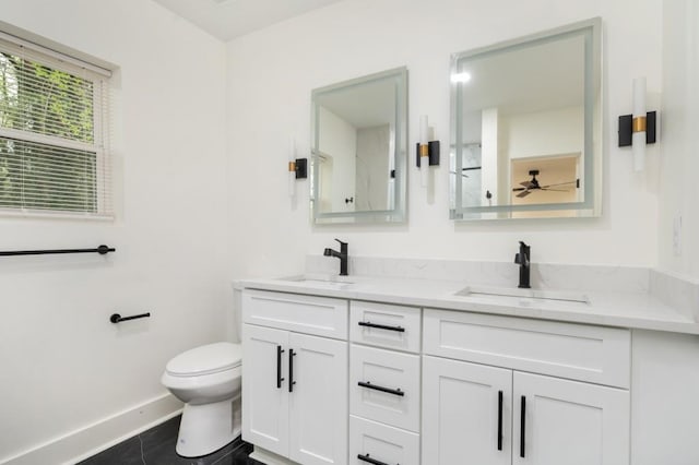 bathroom featuring toilet, baseboards, double vanity, and a sink