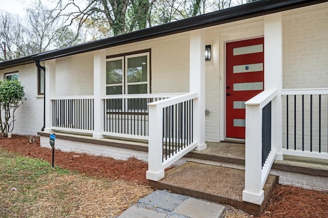 property entrance with a porch and brick siding