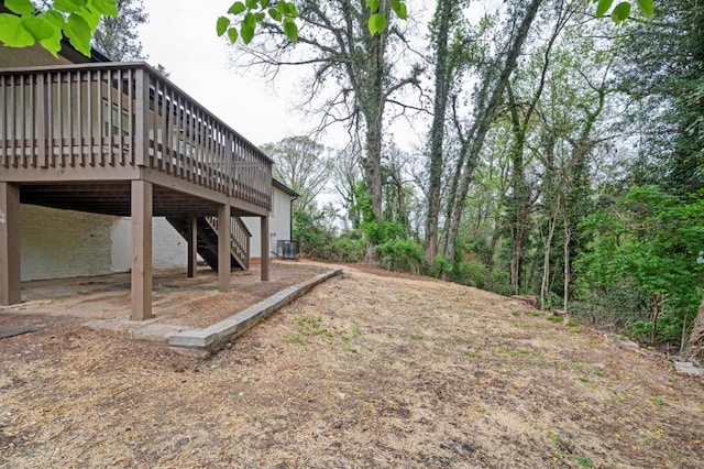 view of yard with central AC unit, a wooden deck, and stairs