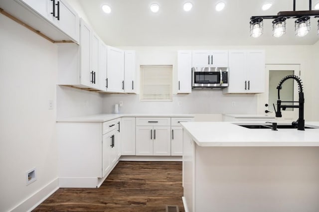 kitchen with a sink, white cabinets, dark wood-style flooring, stainless steel microwave, and recessed lighting
