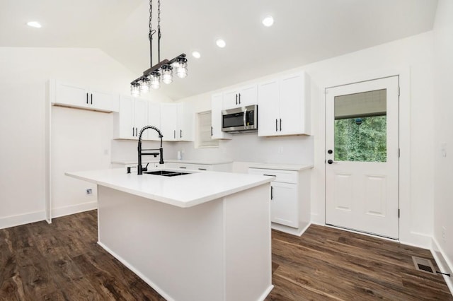 kitchen featuring a sink, stainless steel microwave, white cabinetry, and dark wood finished floors