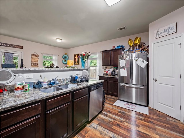 kitchen featuring light stone counters, appliances with stainless steel finishes, dark wood-type flooring, dark brown cabinetry, and sink