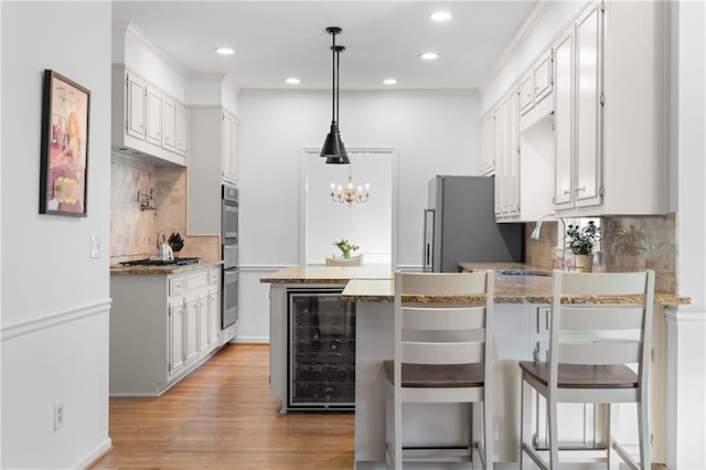 kitchen featuring wine cooler, stainless steel appliances, a peninsula, a sink, and light wood-type flooring