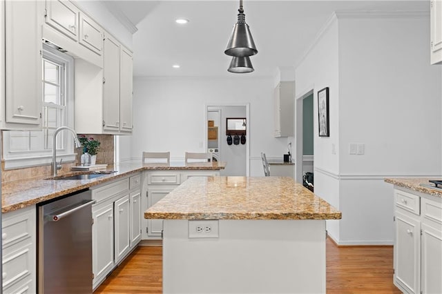 kitchen with a center island, light wood-style flooring, stainless steel dishwasher, ornamental molding, and a sink