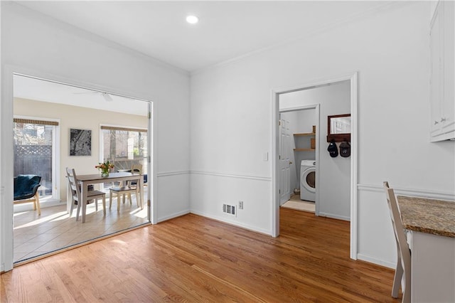 dining area featuring washer / clothes dryer, visible vents, light wood-style flooring, ornamental molding, and baseboards