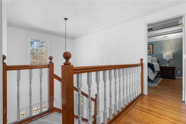 hall with light wood-style flooring, crown molding, and an upstairs landing