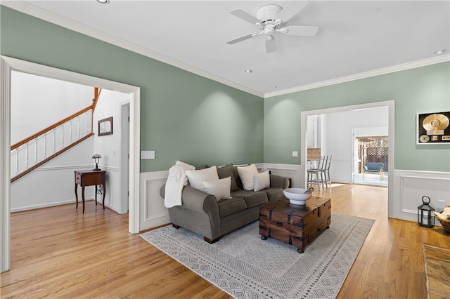 living room featuring a wainscoted wall, ornamental molding, and light wood-style floors