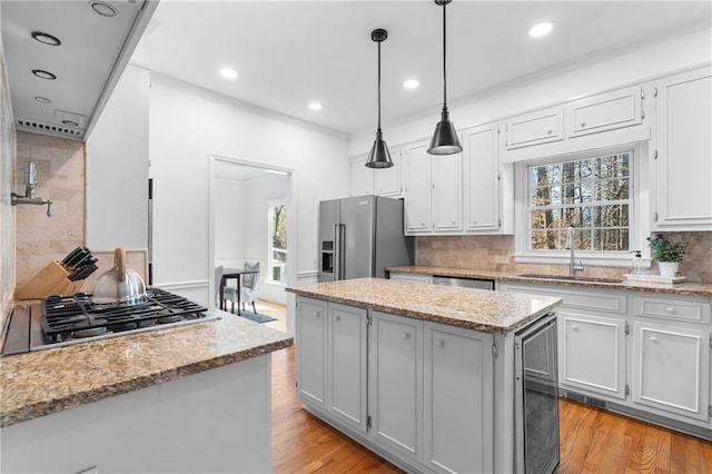 kitchen featuring a kitchen island, appliances with stainless steel finishes, a sink, light wood-style floors, and a wealth of natural light