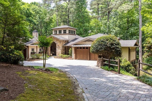 mediterranean / spanish-style house featuring stone siding, decorative driveway, fence, and an attached garage