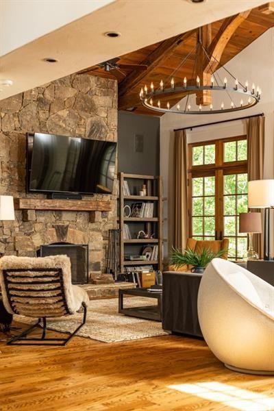 living area featuring lofted ceiling with beams, wooden ceiling, wood finished floors, a stone fireplace, and french doors