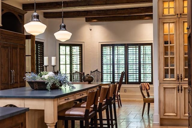 interior space featuring dark countertops, a wealth of natural light, stone tile flooring, and beamed ceiling