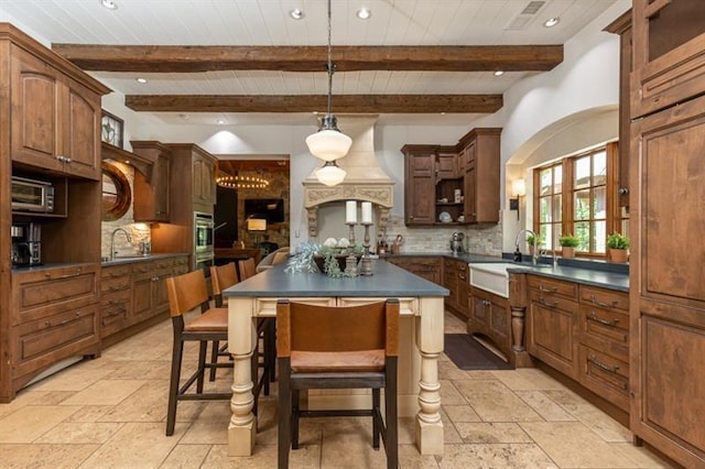 kitchen featuring dark countertops, a sink, stone tile flooring, and decorative backsplash