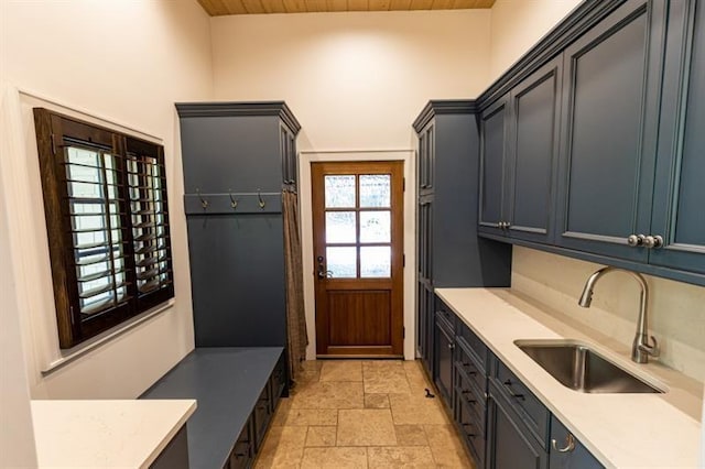 mudroom with stone finish flooring, a sink, and wood ceiling