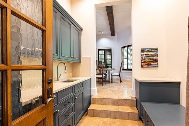 bar with stone finish floor, beam ceiling, a sink, and baseboards