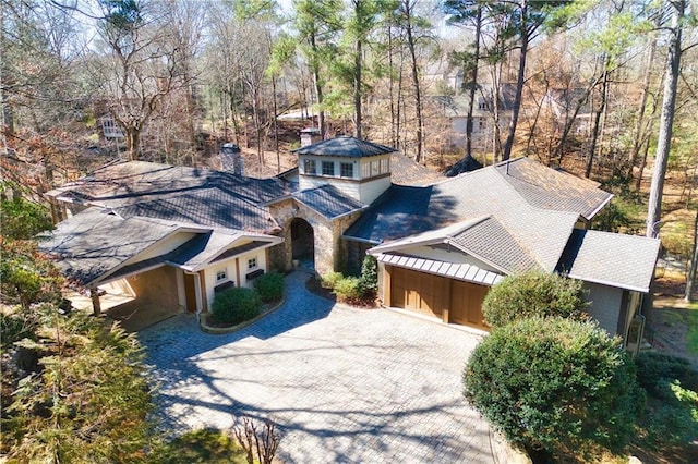 view of front of property featuring decorative driveway, roof with shingles, and an attached garage