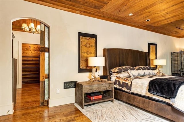 bedroom featuring baseboards, wooden ceiling, wood finished floors, an inviting chandelier, and recessed lighting