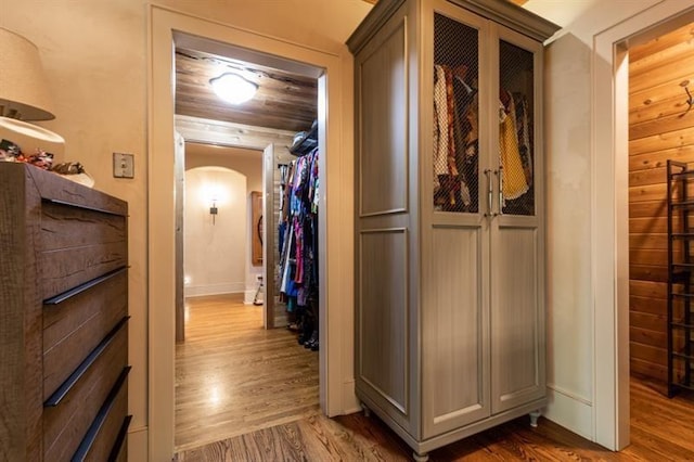 hallway featuring arched walkways and wood finished floors