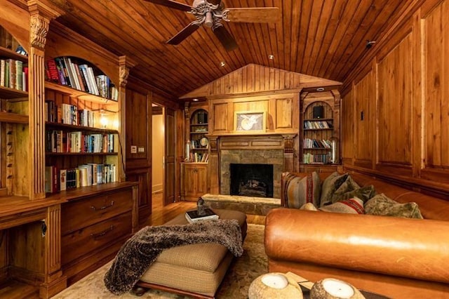 sitting room featuring lofted ceiling, a stone fireplace, wooden walls, wood ceiling, and built in features
