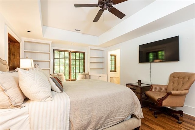 bedroom with a tray ceiling, visible vents, ceiling fan, and wood finished floors