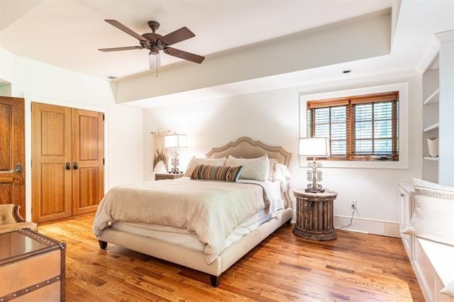 bedroom with ceiling fan, light wood-style flooring, and baseboards