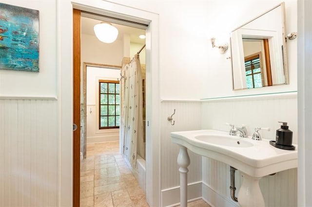 full bath with a wainscoted wall and a shower with shower curtain