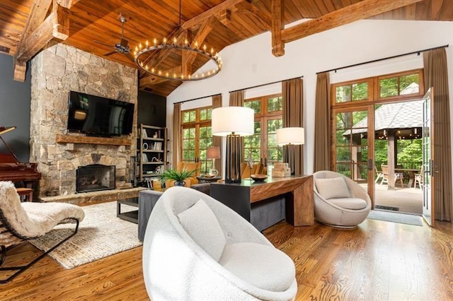 living area featuring beam ceiling, a fireplace, wood finished floors, and wood ceiling