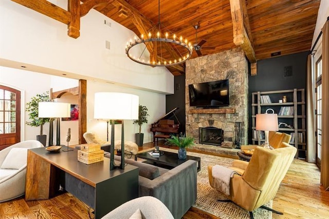 living room featuring wood ceiling, a stone fireplace, wood finished floors, a chandelier, and beamed ceiling