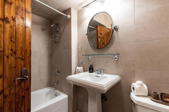 bathroom featuring shower / bathing tub combination, tile walls, and toilet