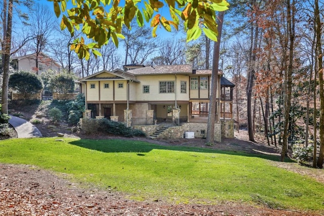back of house with stone siding, a lawn, and stairs