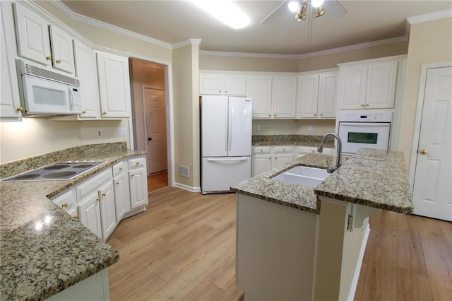 kitchen with light stone countertops, white appliances, white cabinetry, sink, and a kitchen island with sink