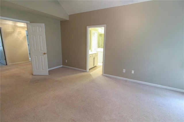 unfurnished bedroom featuring connected bathroom, light carpet, and vaulted ceiling