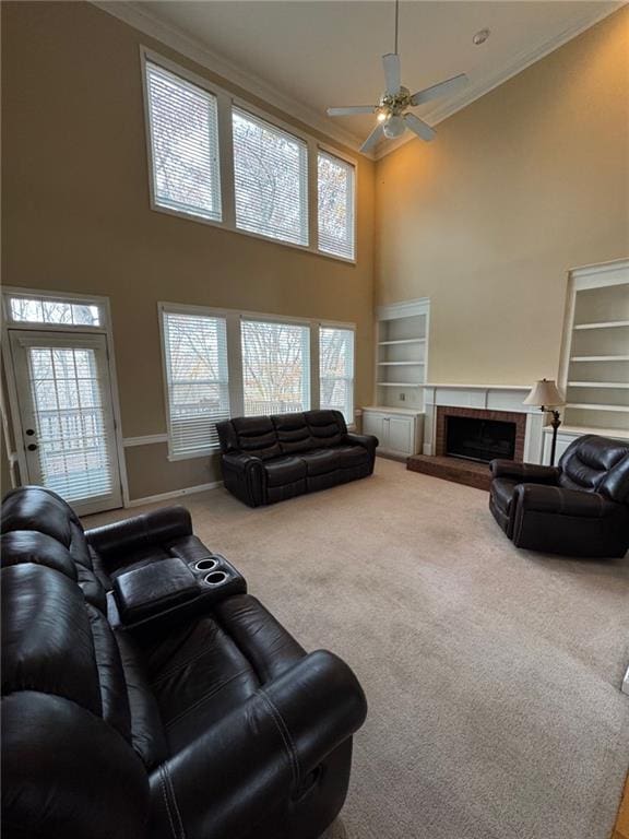 living room with a fireplace, carpet, a high ceiling, ornamental molding, and ceiling fan