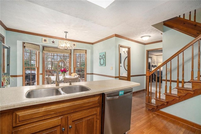 kitchen featuring sink, decorative light fixtures, light hardwood / wood-style flooring, a textured ceiling, and stainless steel dishwasher