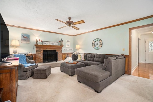 carpeted living room featuring a textured ceiling, a fireplace, ornamental molding, and ceiling fan