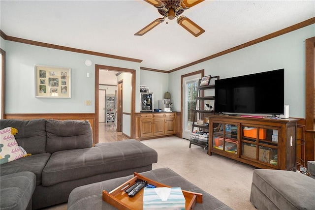 carpeted living room with ornamental molding and ceiling fan