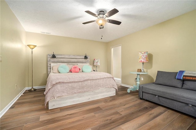 bedroom featuring ceiling fan, dark wood-type flooring, and a textured ceiling