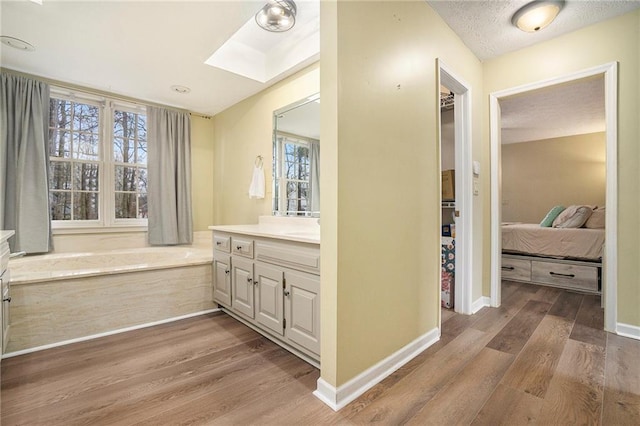 bathroom featuring a skylight, a textured ceiling, vanity, a bathtub, and hardwood / wood-style floors