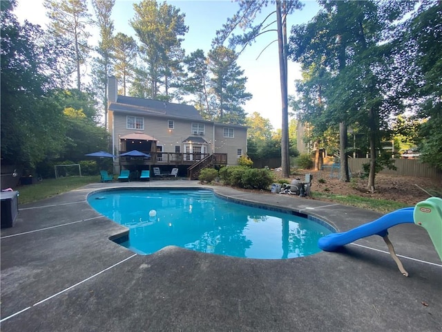 view of swimming pool with a water slide and a deck