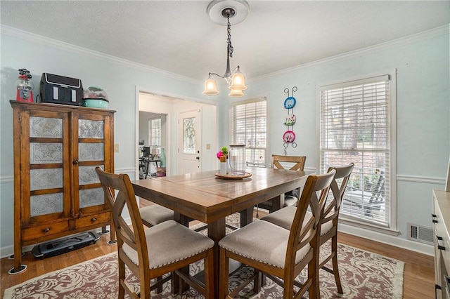 dining area featuring crown molding, an inviting chandelier, and light hardwood / wood-style flooring