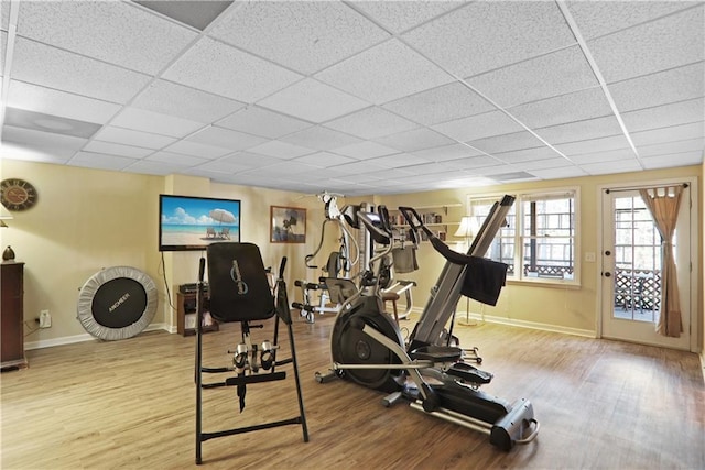 workout room featuring a drop ceiling, light wood-type flooring, and baseboards