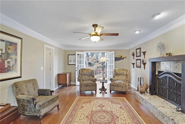 sitting room featuring baseboards, a premium fireplace, ornamental molding, and wood finished floors