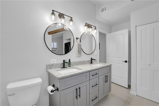 bathroom featuring tile flooring, large vanity, toilet, and double sink