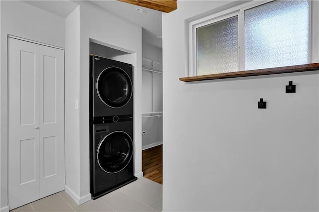 washroom with stacked washer and dryer and light tile floors